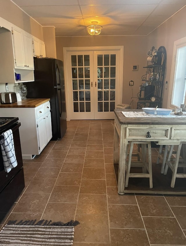 470 Askin Ln, Baxter, TN 38544 - kitchen with french doors, black appliances, white cabinetry, dark tile patterned floors, and wood counters