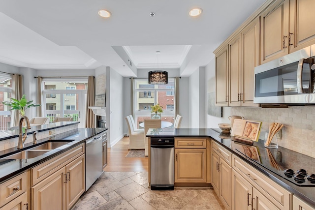110 31st Ave N Unit 301, Nashville, TN 37203 - kitchen with stainless steel appliances, a sink, a tray ceiling, dark countertops, and decorative backsplash