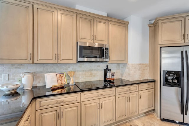 110 31st Ave N Unit 301, Nashville, TN 37203 - kitchen featuring stainless steel appliances, decorative backsplash, cream cabinets, and dark stone countertops