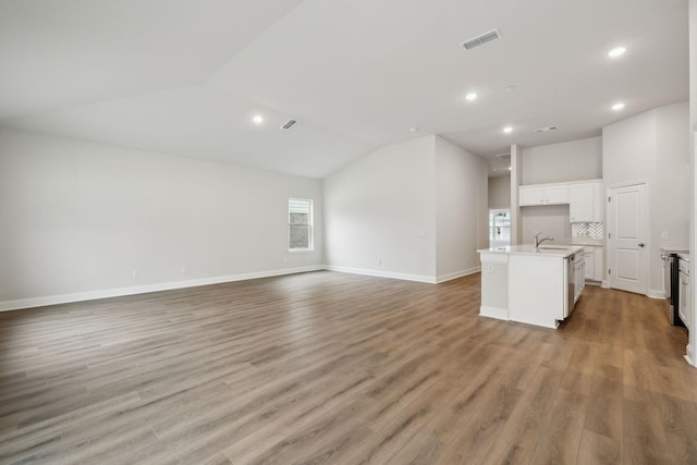 126 Cades Blf, Lebanon, TN 37087 - unfurnished living room with lofted ceiling, recessed lighting, light wood-style flooring, baseboards, and a sink