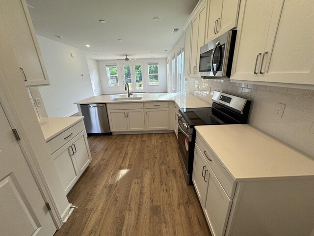 410 Blair Rd, Smyrna, TN 37167 - kitchen with appliances with stainless steel finishes, a sink, a peninsula, wood finished floors, and backsplash