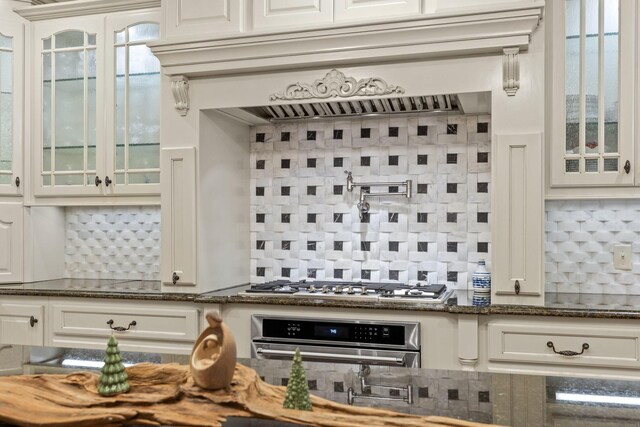 697 N Stewart Ln, Rising Fawn, GA 30738 - kitchen featuring stainless steel appliances, decorative backsplash, glass insert cabinets, dark stone countertops, and white cabinetry