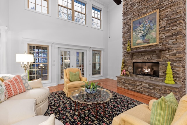 697 N Stewart Ln, Rising Fawn, GA 30738 - living room featuring wood finished floors, a towering ceiling, french doors, a stone fireplace, and baseboards