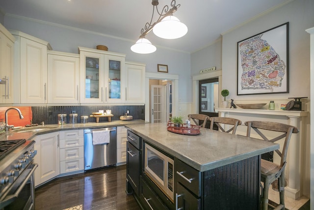 712 W Main St, Franklin, TN 37064 - kitchen with stainless steel appliances, a sink, crown molding, decorative backsplash, and a center island