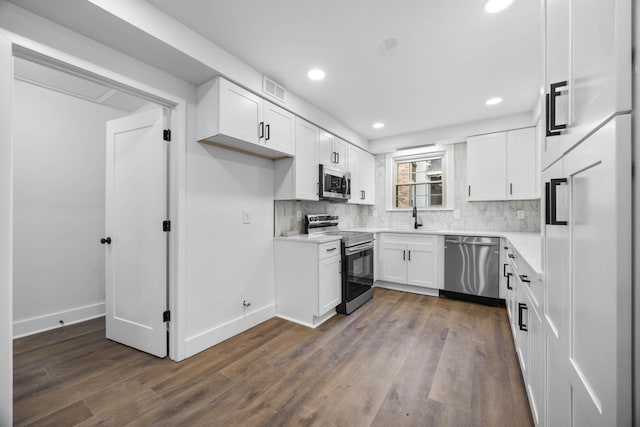 176 Kirby Dr, Clarksville, TN 37042 - kitchen featuring stainless steel appliances, white cabinets, dark wood finished floors, decorative backsplash, and recessed lighting