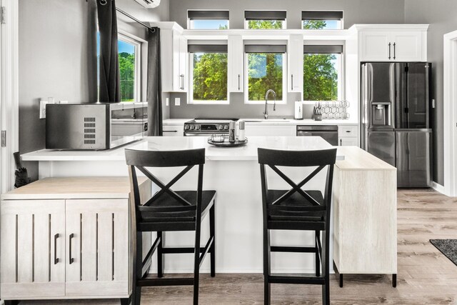 14 Lewter Rd, Taft, TN 38488 - kitchen with appliances with stainless steel finishes, white cabinets, light wood-style flooring, a sink, and a breakfast bar