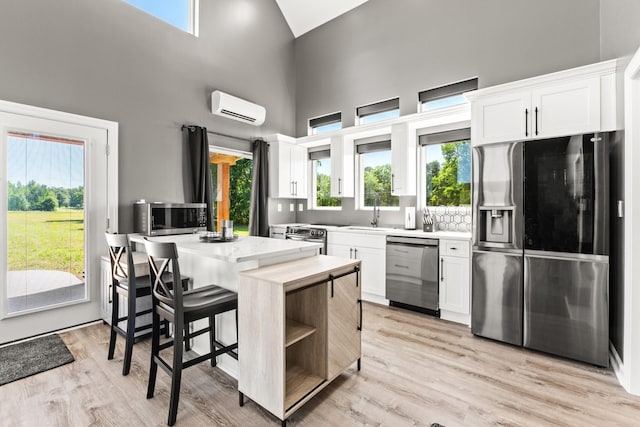 14 Lewter Rd, Taft, TN 38488 - kitchen with stainless steel appliances, an AC wall unit, white cabinetry, a high ceiling, and light wood-type flooring