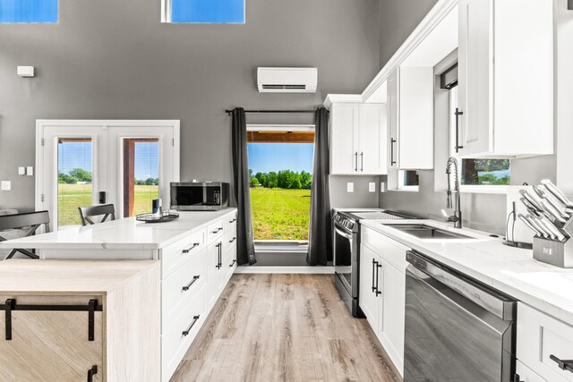 14 Lewter Rd, Taft, TN 38488 - kitchen featuring appliances with stainless steel finishes, a sink, a wall mounted AC, a towering ceiling, and light wood-style floors