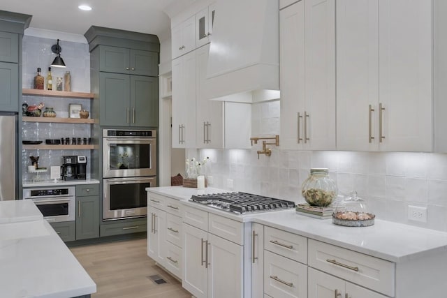 9906 Amarosa Ct, Brentwood, TN 37027 - kitchen featuring appliances with stainless steel finishes, custom exhaust hood, decorative backsplash, open shelves, and light wood-style flooring