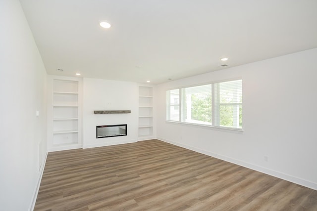 124 W Cassa Way, Mount Juliet, TN 37122 - unfurnished living room with baseboards, built in shelves, wood finished floors, recessed lighting, and a glass covered fireplace