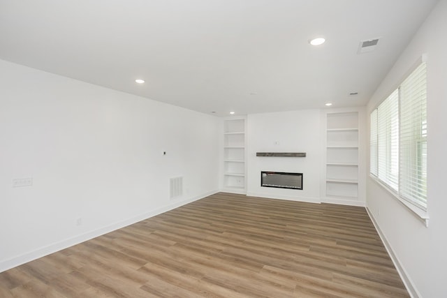 124 W Cassa Way, Mount Juliet, TN 37122 - unfurnished living room featuring light wood-style floors, a glass covered fireplace, baseboards, recessed lighting, and built in shelves