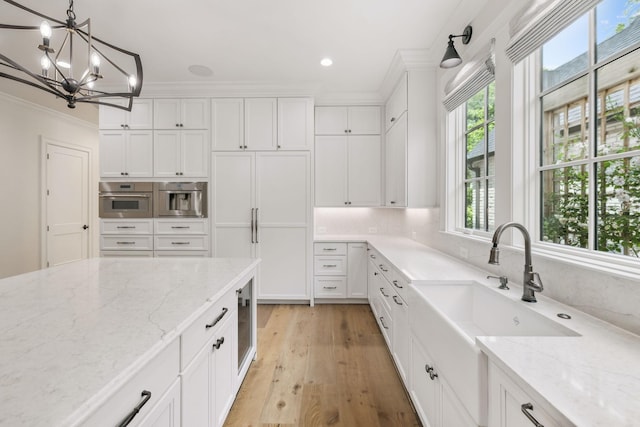 304 Berry Cir, Franklin, TN 37064 - kitchen with crown molding, white cabinets, a chandelier, stainless steel oven, and light wood finished floors