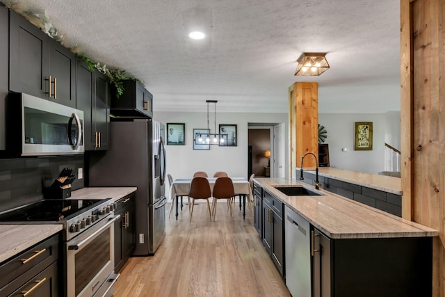 1800 Old Highway 52, Lafayette, TN 37083 - kitchen with stainless steel appliances, a sink, a textured ceiling, light wood-style floors, and backsplash