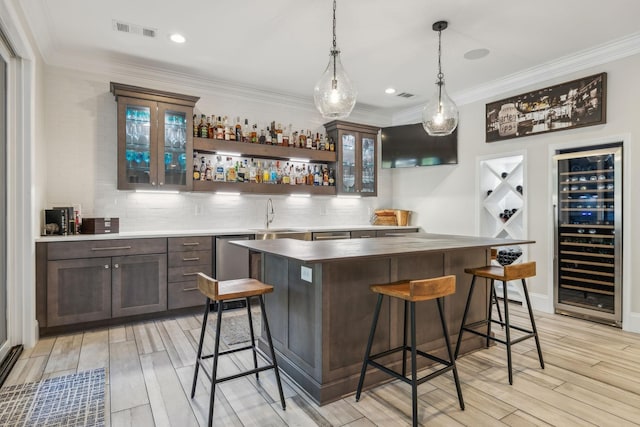 424 Wild Elm St, Franklin, TN 37064 - indoor wet bar featuring beverage cooler, light wood finished floors, tasteful backsplash, hanging light fixtures, and crown molding