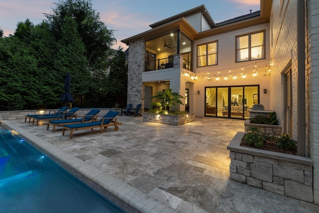 424 Wild Elm St, Franklin, TN 37064 - back of property at dusk featuring a balcony, a patio area, an outdoor pool, and ceiling fan