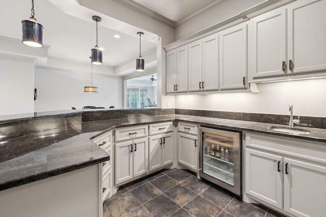 8704 Wolfsbane Ln, College Grove, TN 37046 - kitchen featuring beverage cooler, ornamental molding, hanging light fixtures, a raised ceiling, and dark stone counters