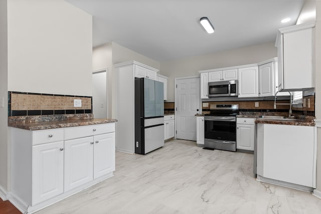 2905 Burtonwood Dr, Spring Hill, TN 37174 - kitchen featuring appliances with stainless steel finishes, a sink, tasteful backsplash, white cabinets, and light marble finish flooring