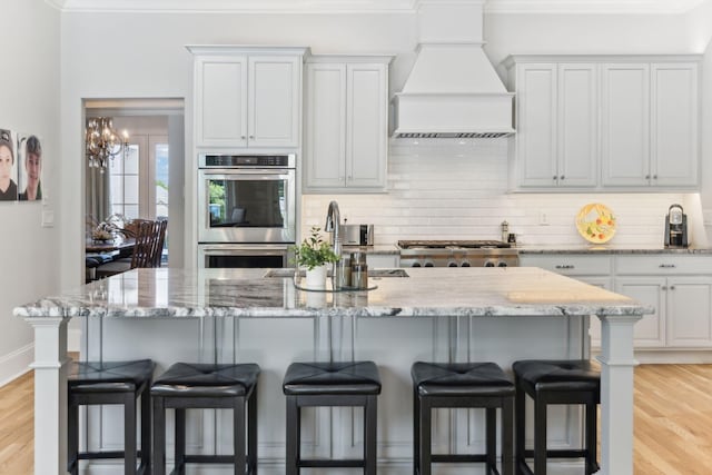 4043 Old Light Cir, Arrington, TN 37014 - kitchen featuring appliances with stainless steel finishes, premium range hood, a kitchen bar, backsplash, and crown molding