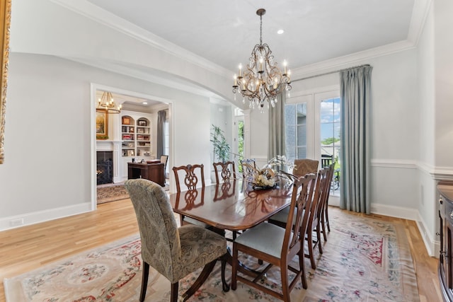 4043 Old Light Cir, Arrington, TN 37014 - dining space featuring light wood-style flooring, a chandelier, crown molding, arched walkways, and a warm lit fireplace