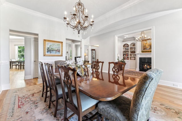 4043 Old Light Cir, Arrington, TN 37014 - dining space featuring light wood-style flooring, crown molding, a chandelier, a warm lit fireplace, and baseboards