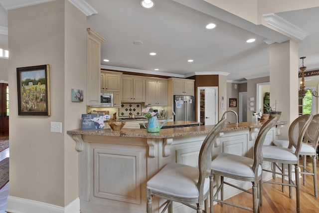 3285 Blazer Rd, Franklin, TN 37064 - kitchen featuring appliances with stainless steel finishes, cream cabinets, crown molding, a peninsula, and light wood-style flooring
