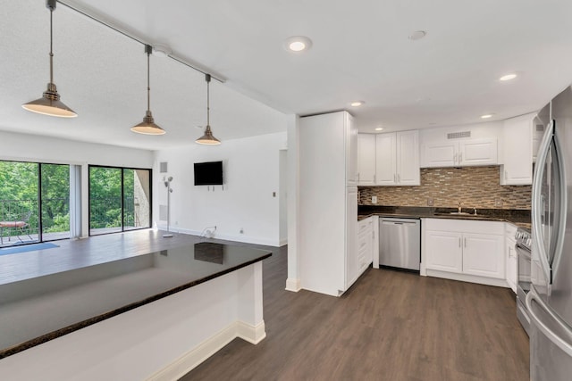 6666 Brookmont Ter Unit 307, Nashville, TN 37205 - kitchen featuring appliances with stainless steel finishes, dark countertops, a sink, dark wood finished floors, and pendant lighting