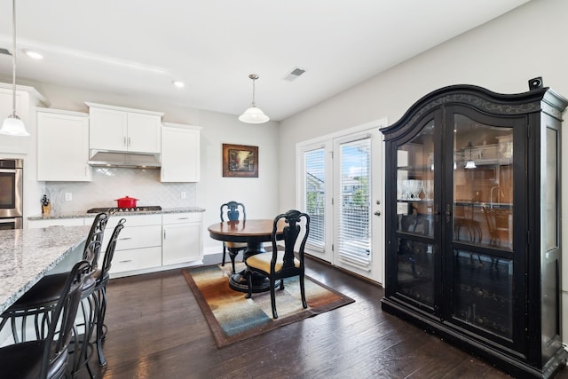 633 Fall Creek Cir, Goodlettsville, TN 37072 - kitchen with light stone counters, tasteful backsplash, under cabinet range hood, white cabinetry, and hanging light fixtures