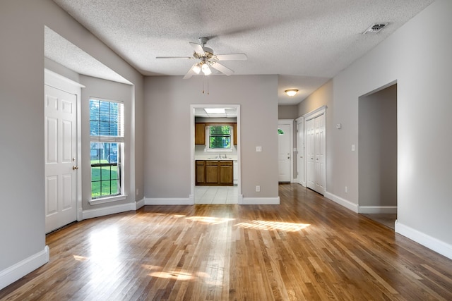 504 Macfie Ct, Madison, TN 37115 - unfurnished living room featuring light wood-style floors, ceiling fan, a sink, baseboards, and a textured ceiling