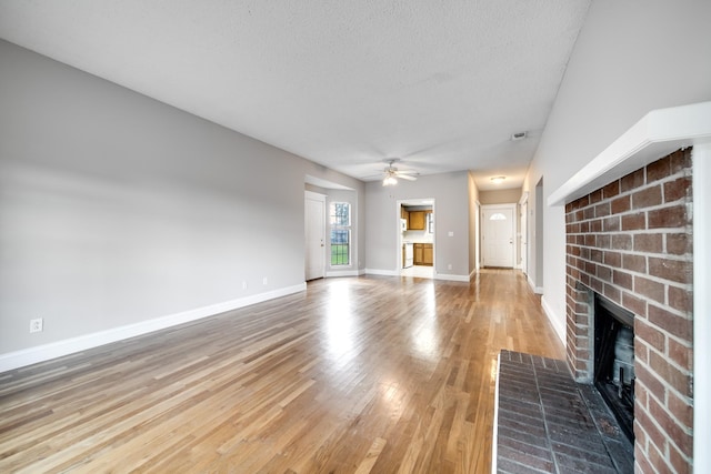 504 Macfie Ct, Madison, TN 37115 - unfurnished living room with a fireplace, ceiling fan, light wood-style floors, baseboards, and a textured ceiling