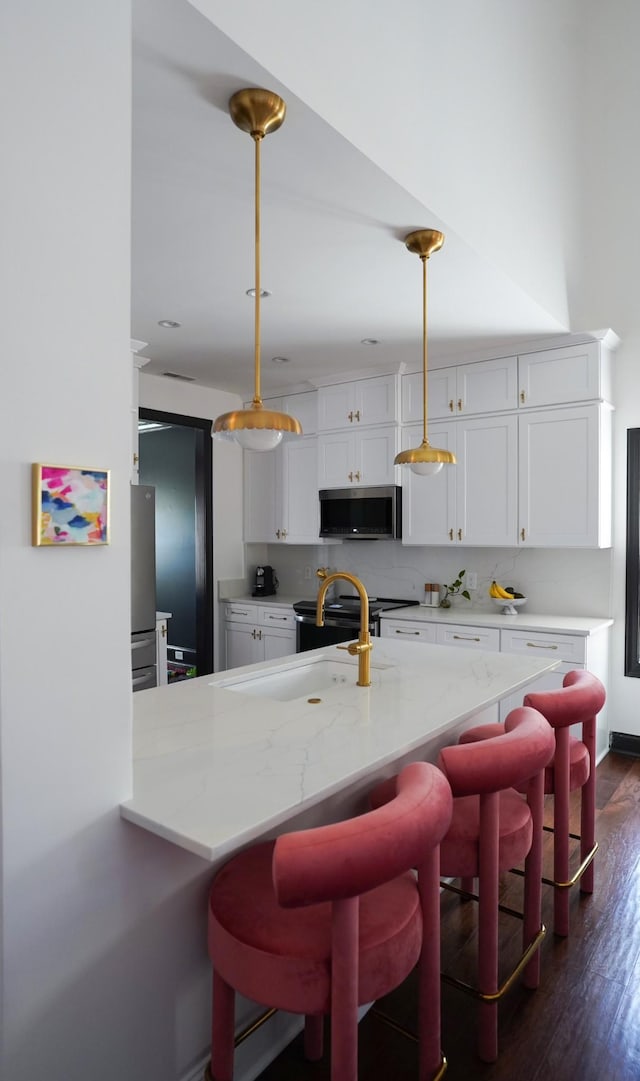 173 Tulip Grove Pt, Hermitage, TN 37076 - kitchen with stainless steel microwave, white cabinetry, dark wood finished floors, light stone countertops, and a kitchen bar
