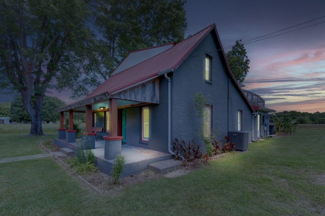 490 Shady Grove Rd, Manchester, TN 37355 - property exterior at dusk with brick siding, a lawn, central air condition unit, metal roof, and a patio