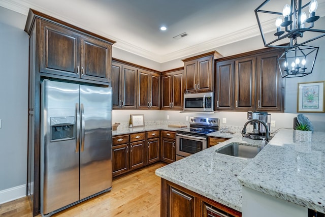 105 Andrews Dr, Loretto, TN 38469 - kitchen with appliances with stainless steel finishes, a sink, a chandelier, light stone counters, and dark brown cabinetry