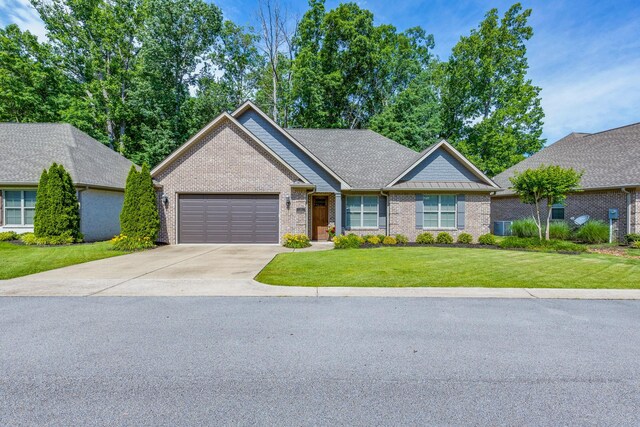 105 Andrews Dr, Loretto, TN 38469 - view of front of property featuring a garage, brick siding, driveway, a front lawn, and cooling unit