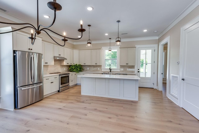 110 4th Ave S, Loretto, TN 38469 - kitchen featuring appliances with stainless steel finishes, under cabinet range hood, ornamental molding, light countertops, and a kitchen island