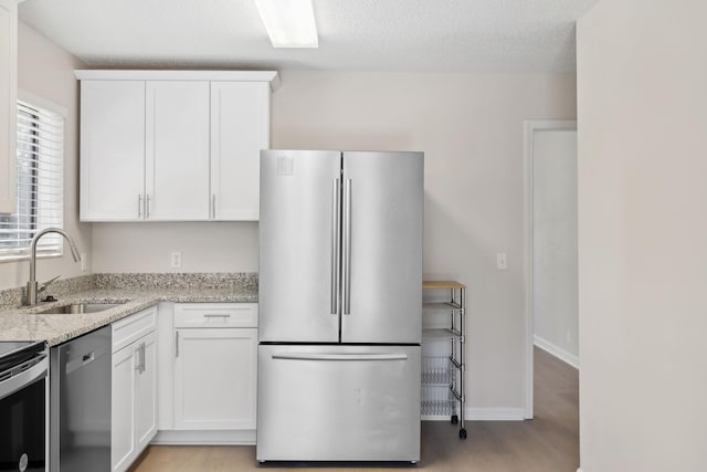 804 Beazer Ln, Antioch, TN 37013 - kitchen featuring stainless steel appliances, light stone countertops, a sink, white cabinetry, and light wood finished floors