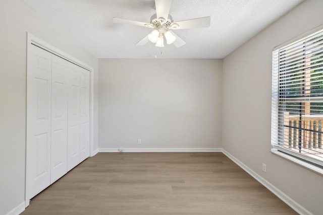 804 Beazer Ln, Antioch, TN 37013 - unfurnished bedroom featuring multiple windows, light wood-style flooring, a closet, a textured ceiling, and ceiling fan