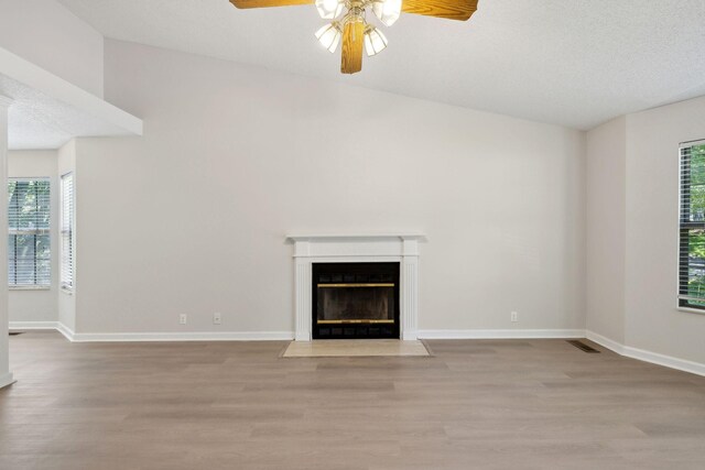 804 Beazer Ln, Antioch, TN 37013 - unfurnished living room featuring a ceiling fan, wood finished floors, plenty of natural light, a fireplace with flush hearth, and a textured ceiling