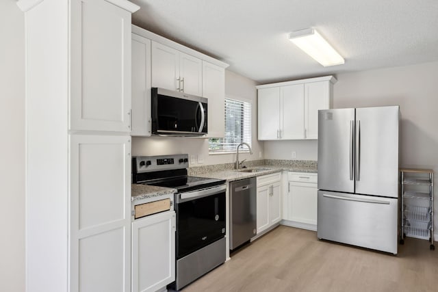 804 Beazer Ln, Antioch, TN 37013 - kitchen featuring appliances with stainless steel finishes, a sink, light wood-style flooring, white cabinetry, and a textured ceiling