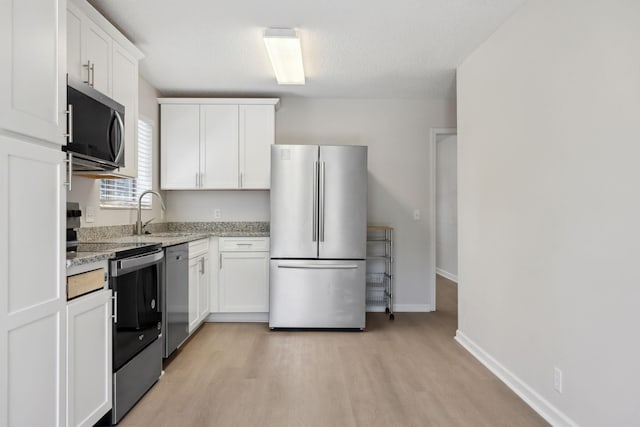 804 Beazer Ln, Antioch, TN 37013 - kitchen with stainless steel appliances, a sink, white cabinets, light wood-style floors, and baseboards
