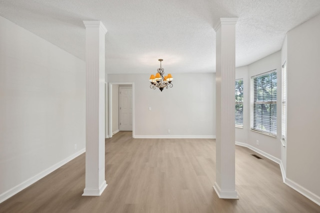 804 Beazer Ln, Antioch, TN 37013 - unfurnished dining area with ornate columns, light wood-style flooring, a textured ceiling, a chandelier, and baseboards