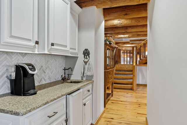 562 Rocky Ridge Rd E, Rock Island, TN 38581 - kitchen featuring a sink, rustic walls, light wood finished floors, white cabinets, and backsplash