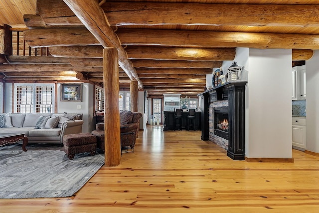 562 Rocky Ridge Rd E, Rock Island, TN 38581 - living area with log walls, light wood-style flooring, wooden ceiling with exposed beams, and a warm lit fireplace