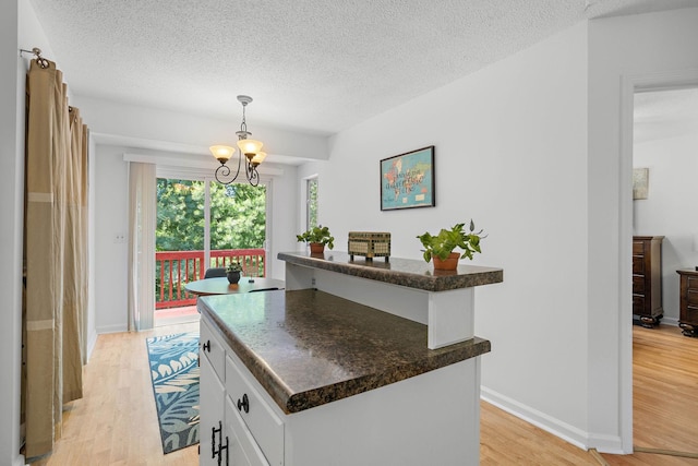 684 Dutchmans Dr, Hermitage, TN 37076 - kitchen with light wood-style flooring, white cabinets, a textured ceiling, a chandelier, and baseboards
