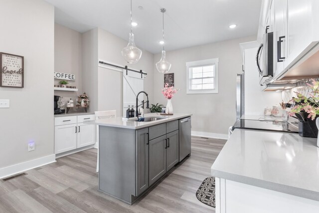 207 Charleston Ave, Pleasant View, TN 37146 - kitchen featuring a sink, a barn door, stainless steel appliances, light wood finished floors, and white cabinets