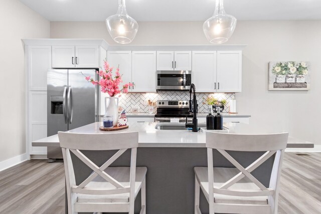 207 Charleston Ave, Pleasant View, TN 37146 - kitchen featuring stainless steel appliances, tasteful backsplash, light wood-type flooring, white cabinets, and a kitchen breakfast bar
