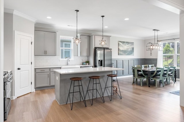 883 Plowson Rd, Mount Juliet, TN 37122 - kitchen with gray cabinets, stainless steel appliances, ornamental molding, a breakfast bar, and light countertops