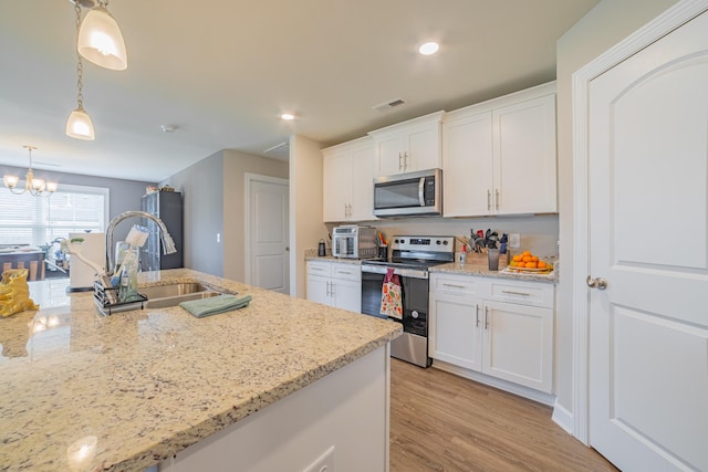 82 Pinnacle Point Ln, Tullahoma, TN 37388 - kitchen with stainless steel appliances, a sink, white cabinets, a chandelier, and light stone counters