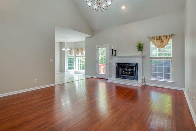 5409 Oak Chase Dr, Antioch, TN 37013 - unfurnished living room with a chandelier, wood finished floors, a fireplace with raised hearth, high vaulted ceiling, and baseboards