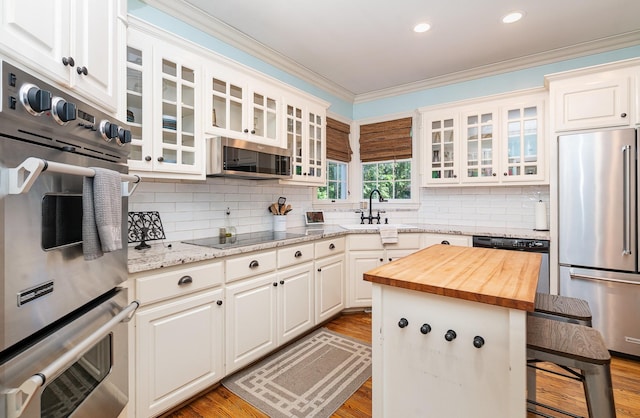 256 Scenic Dr, Dickson, TN 37055 - kitchen featuring appliances with stainless steel finishes, a sink, wood counters, ornamental molding, and a kitchen bar