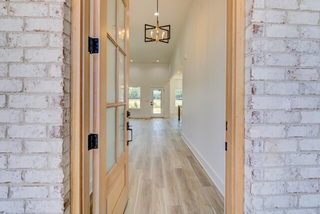 296 Lookout Dr, Winchester, TN 37398 - hall with light wood finished floors, a chandelier, brick wall, and baseboards